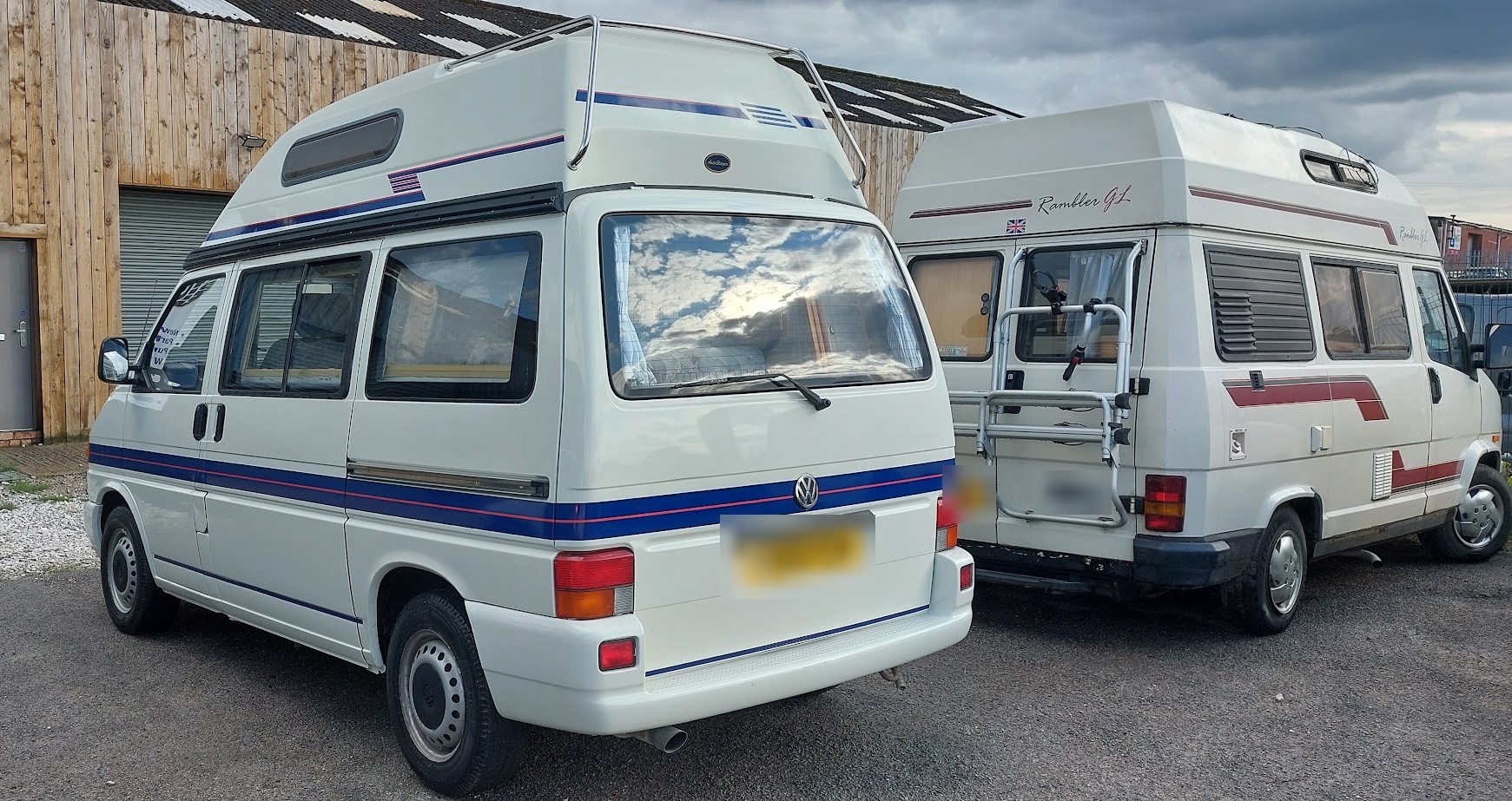 Two white campervans parked outside the workshop unit