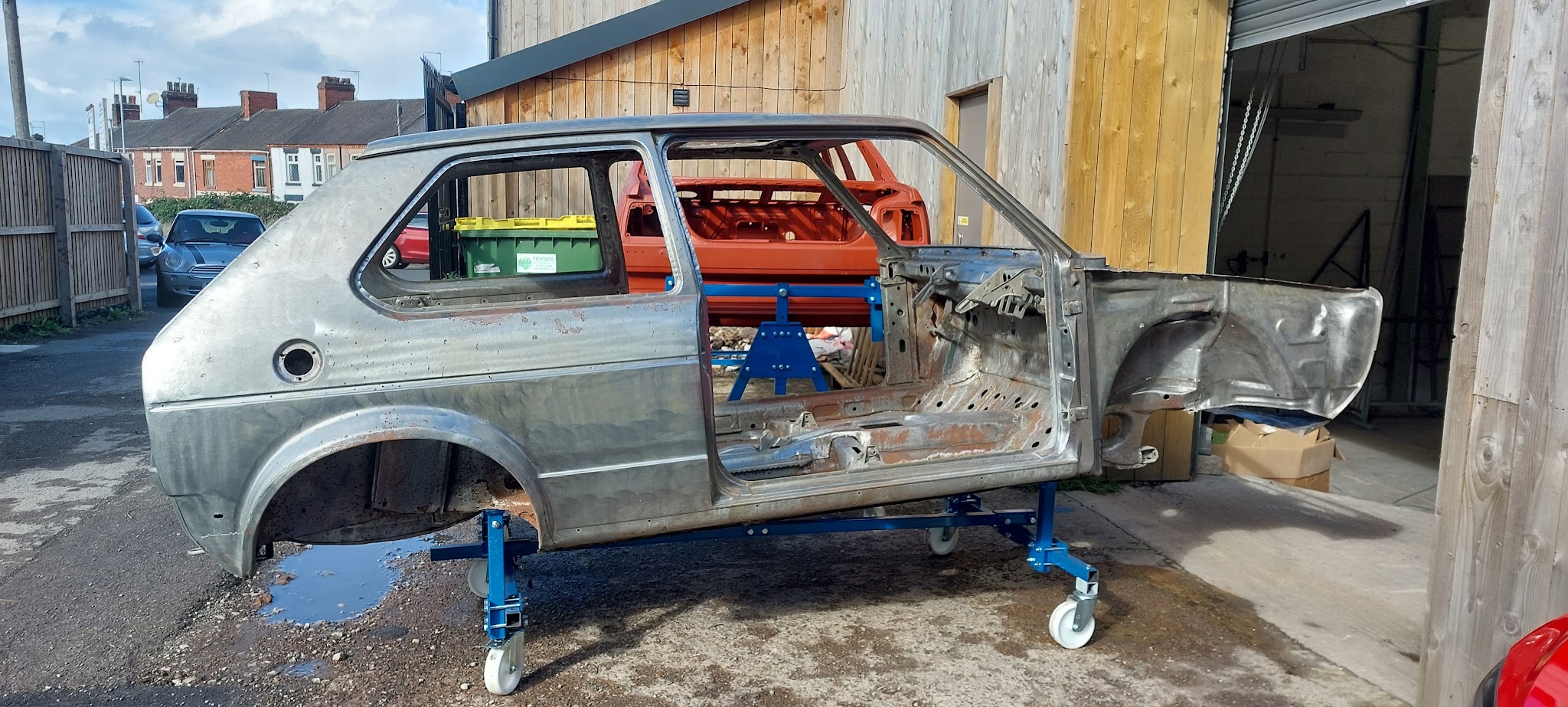 Stripped classic VW Golf shell on a dolly outside the workshop