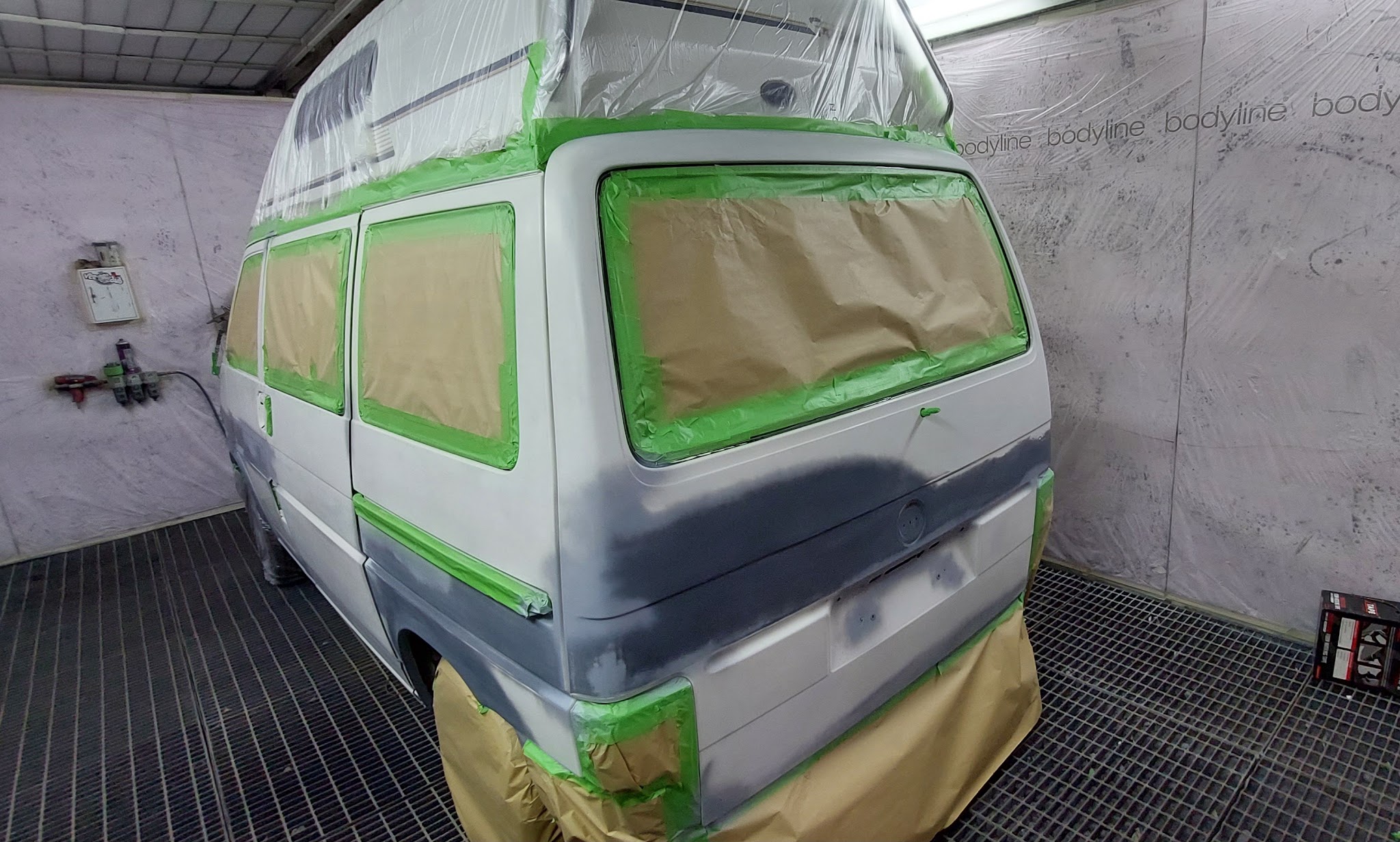 Campervan taped and papered, in primer, in the paint booth