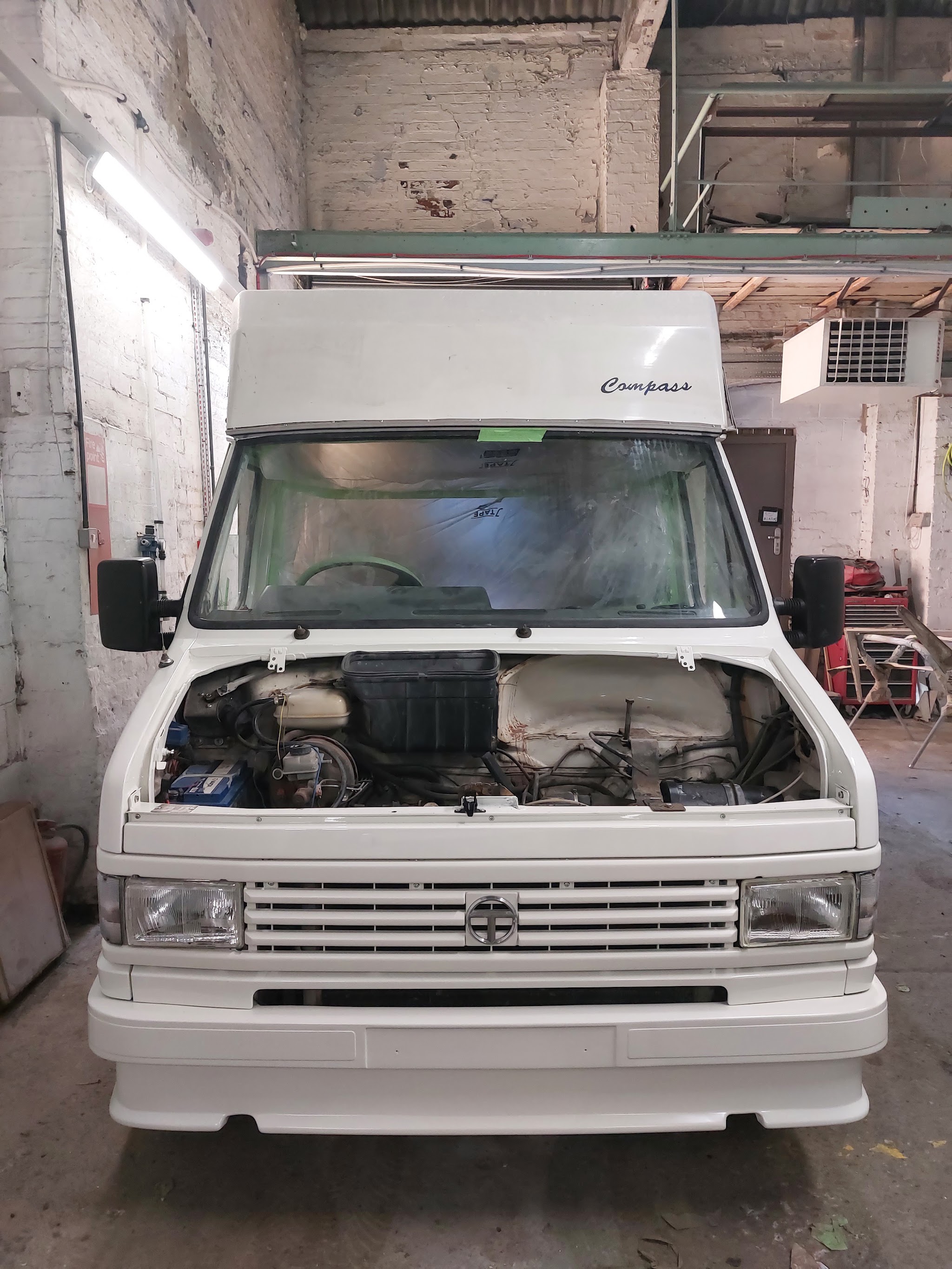White classic campervan inside the workshop with its bonnet open